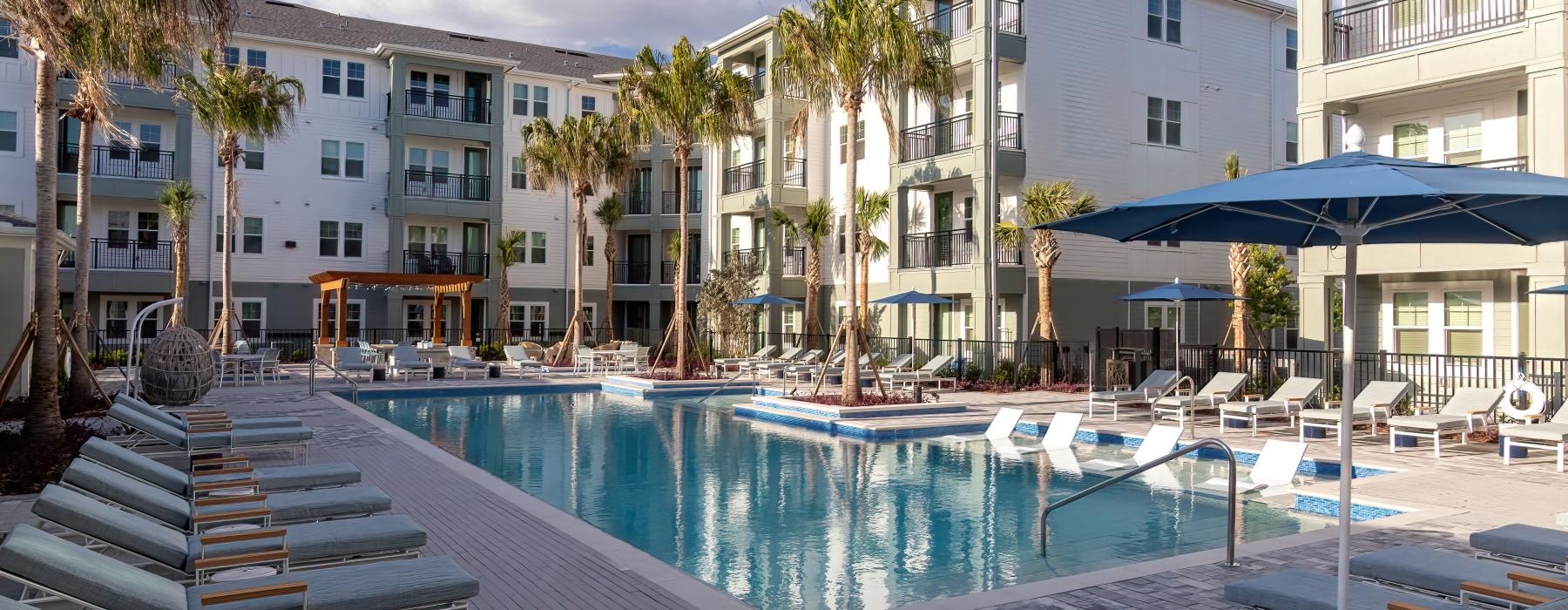 a pool with chairs and umbrellas by a building