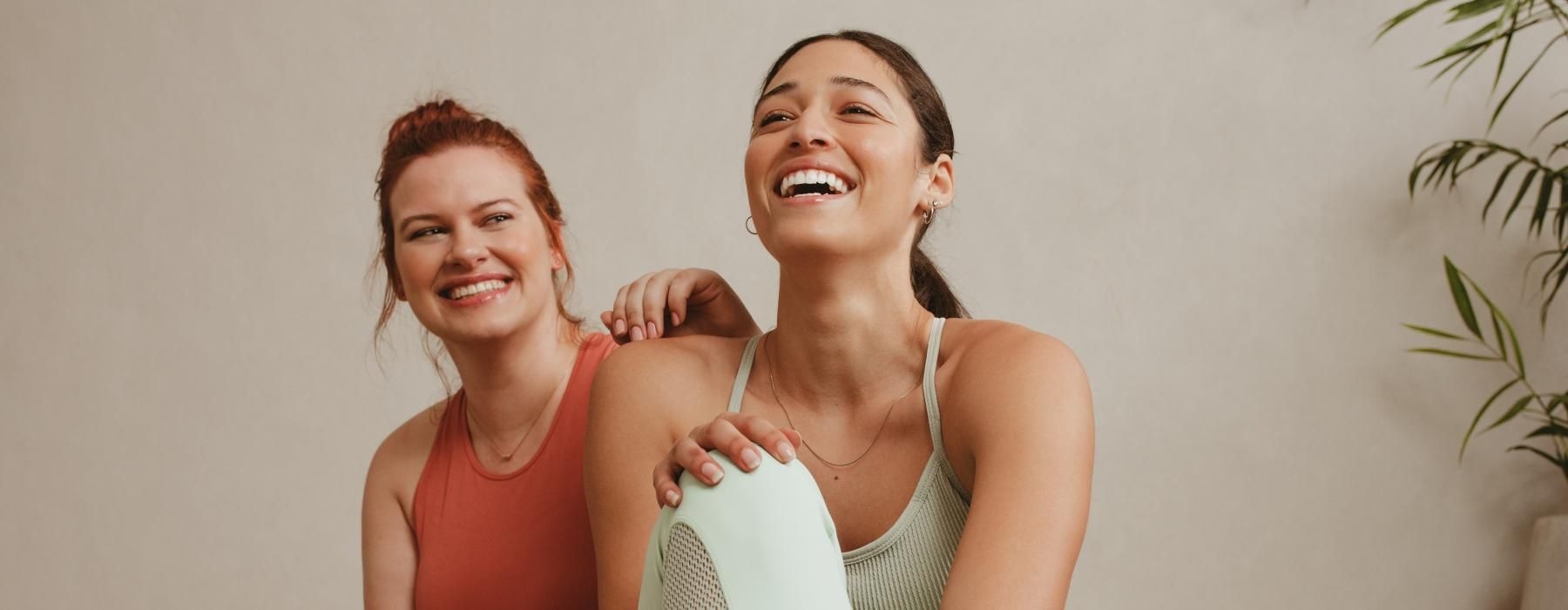 a couple of women sitting on a yoga mat